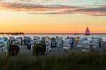 Sonnenuntergang über dem Strand mit Strandkörben und Segelboote